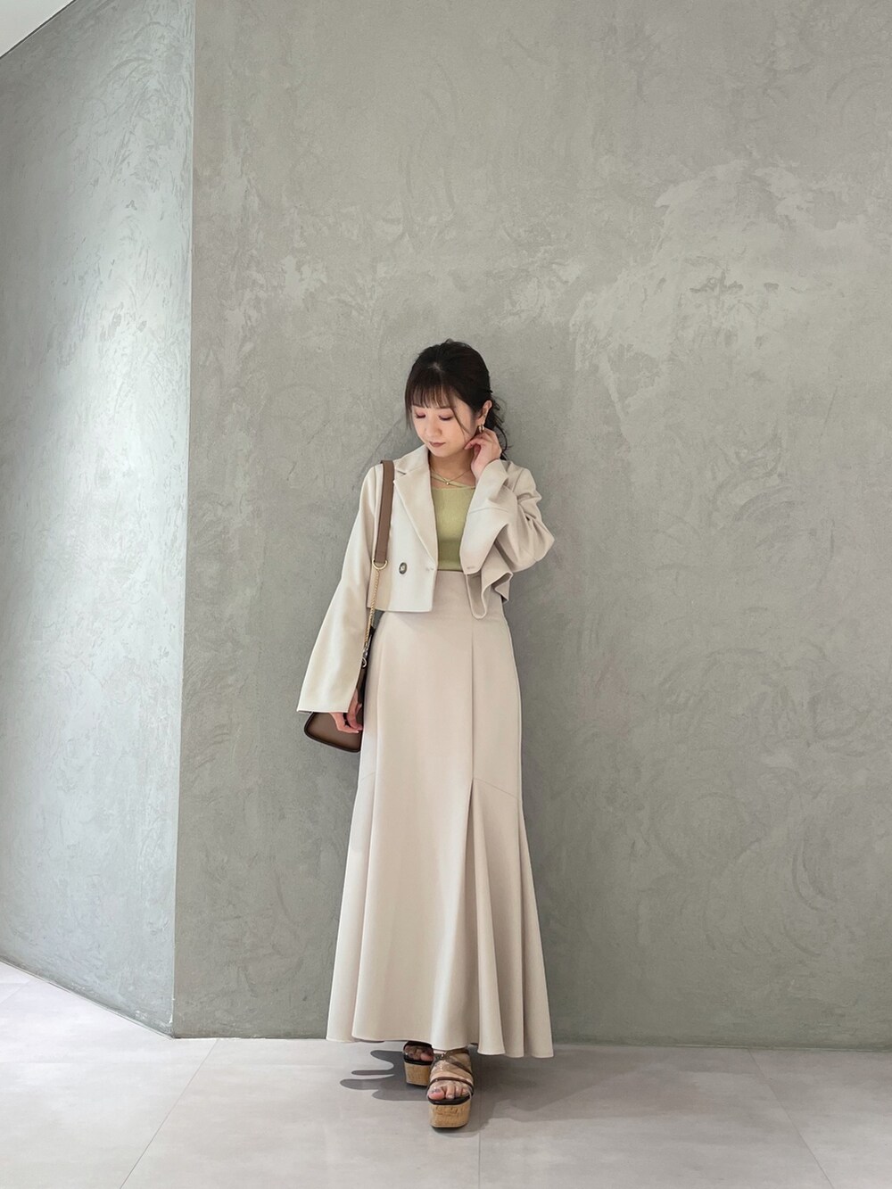 ブラック系のサンダル、ベージュ系のスカート、イエロー系のニット/セーターを着用したレディースの春コーディネートの4枚目の写真