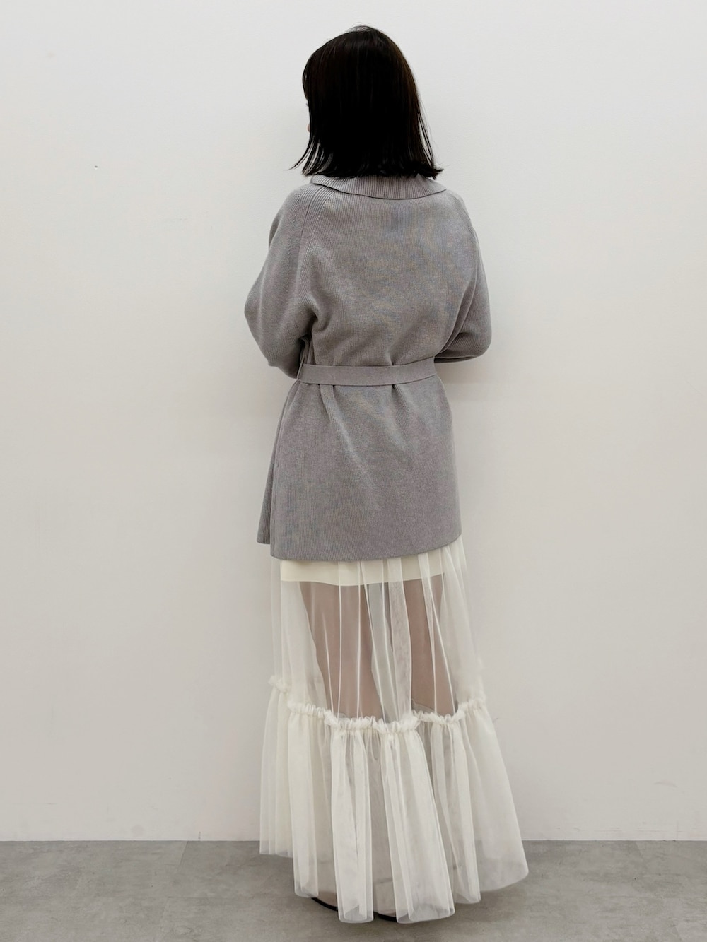 グレー系のニット/セーター、グレー系のブーツ、ホワイト系のスカートを着用したレディースの秋コーディネートの7枚目の写真