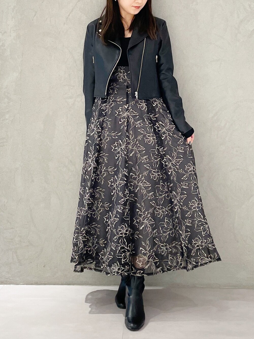 グレー系のスカート、ブラック系のライダースジャケット、ブラック系のブーツを着用したレディースの冬コーディネートの6枚目の写真