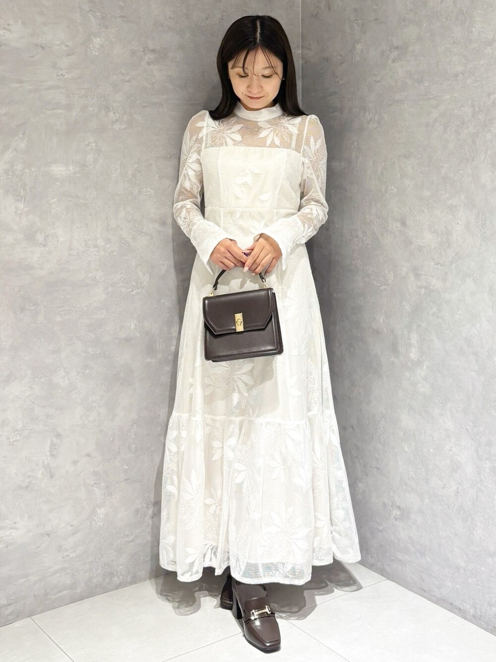 ホワイト系のワンピース、ブラウン系のハンドバッグ、ブラウン系のブーツを着用したレディースの冬コーディネートの7枚目の写真