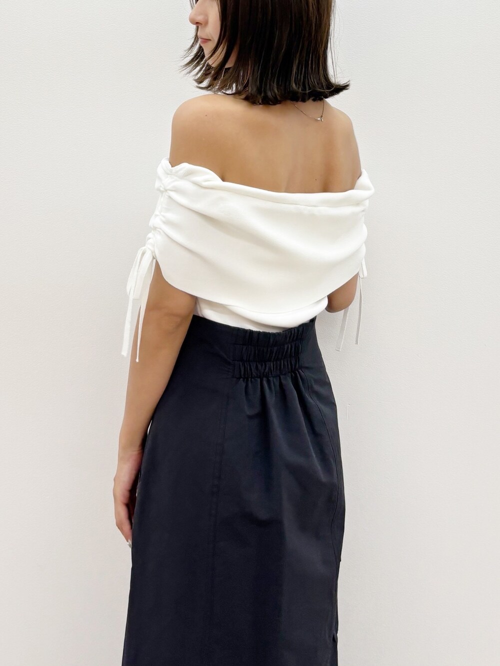 ブラック系のスカート、ホワイト系のニット/セーターを着用したレディースの夏コーディネートの7枚目の写真