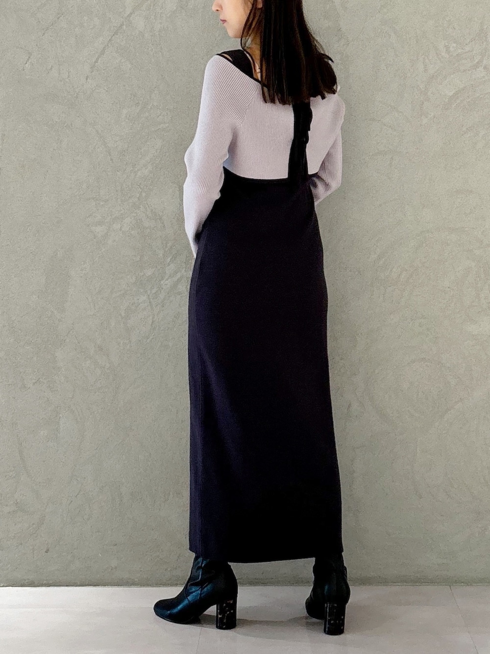 グレー系のワンピース、ブラック系のブーツ、ホワイト系のハンドバッグを着用したレディースの秋コーディネートの2枚目の写真