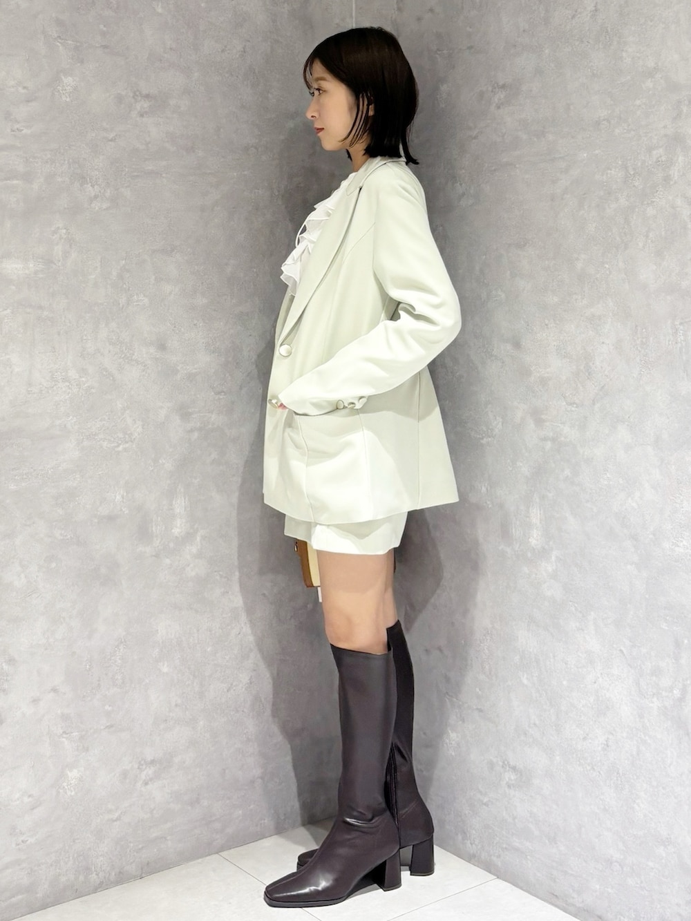 グリーン系のスカート、ブラウン系のブーツ、グリーン系のテーラードジャケットを着用したレディースの春コーディネートの4枚目の写真