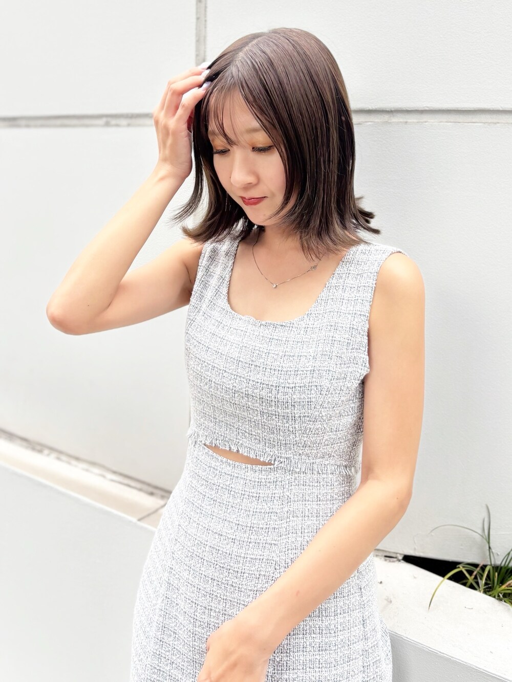 グレー系のワンピース、ホワイト系のサンダル、ブラック系のハンドバッグを着用したレディースの夏コーディネートの4枚目の写真