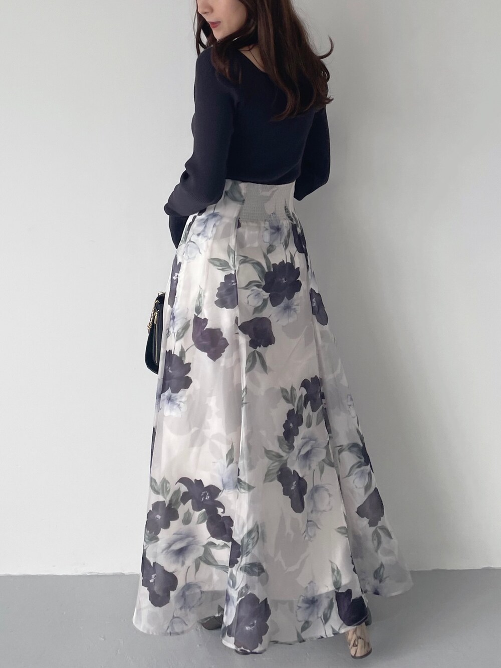 ブルー系のスカート、ブラウン系のブーツ、ブラック系のショルダーバッグを着用したレディースの秋コーディネートの2枚目の写真