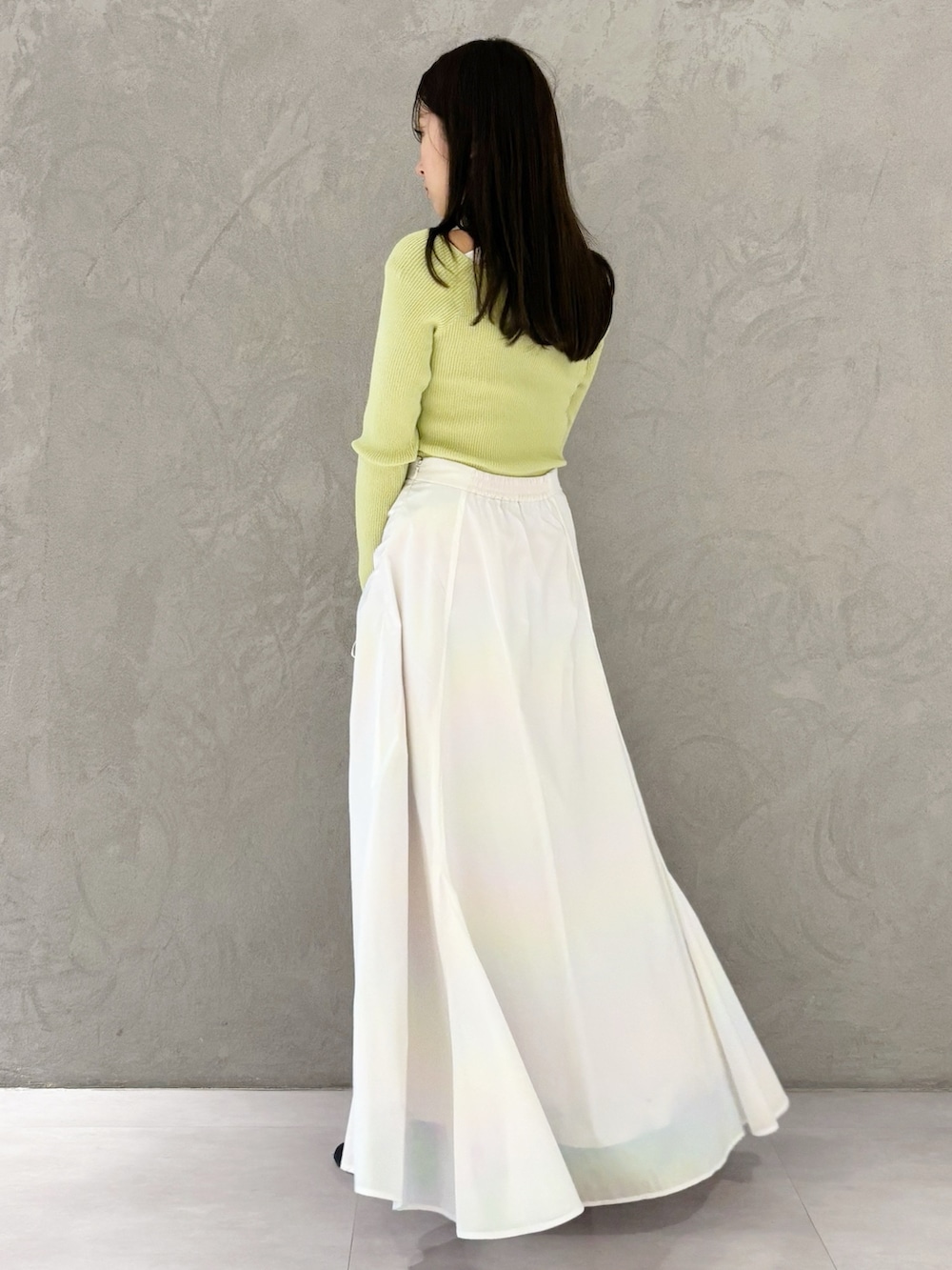 ホワイト系のスカート、ブラック系のブーツ、ブラウン系のハンドバッグを着用したレディースの冬コーディネートの5枚目の写真