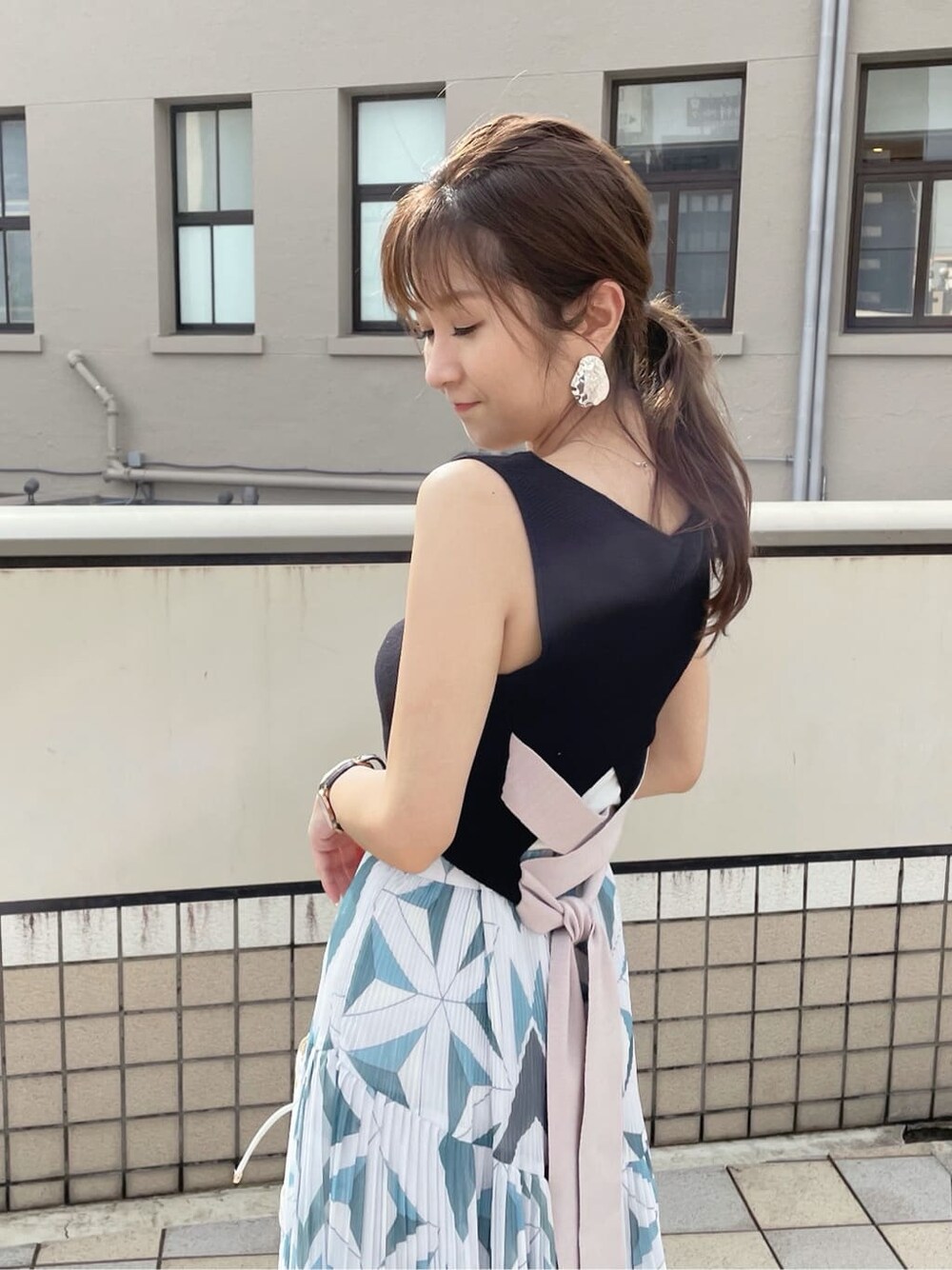ブルー系のスカート、ホワイト系のハンドバッグ、ブラック系のニット/セーターを着用したレディースの夏コーディネートの2枚目の写真