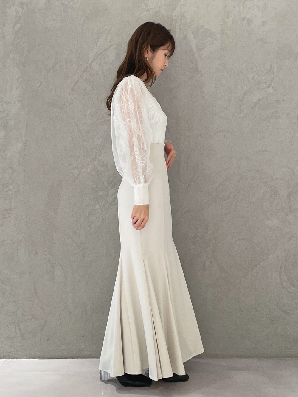 ホワイト系のスカート、ホワイト系のカーディガン/ボレロ、ブラック系のブーツを着用したレディースの冬コーディネートの4枚目の写真