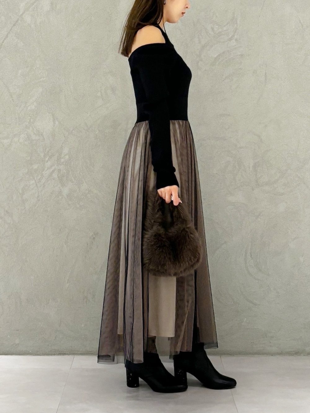 ブラック系のワンピース、ブラック系のブーツ、ブラウン系のハンドバッグを着用したレディースの秋コーディネートの3枚目の写真