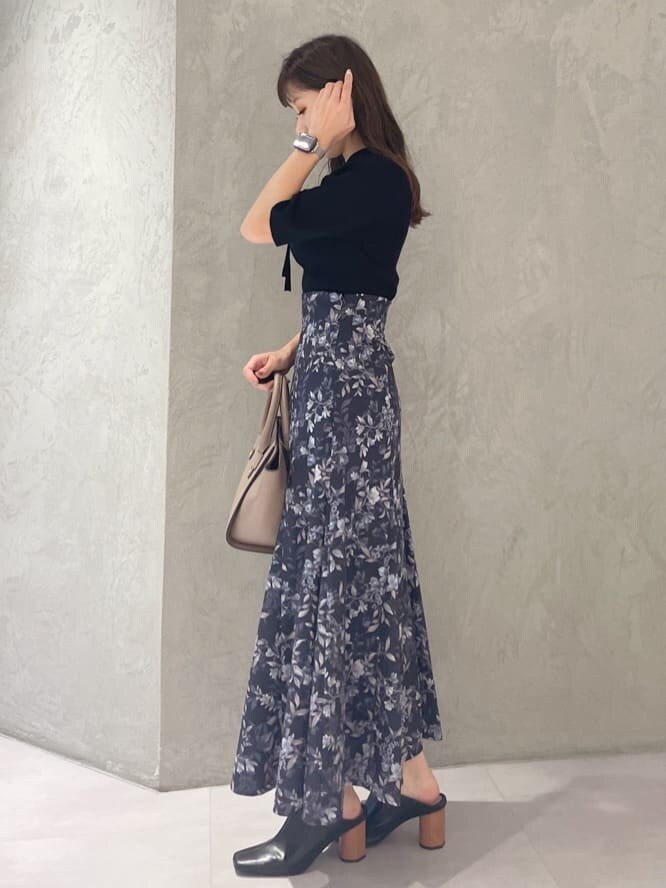 ブラック系のニット/セーター、ブラウン系のハンドバッグ、ブルー系のスカートを着用したレディースの夏コーディネートの4枚目の写真