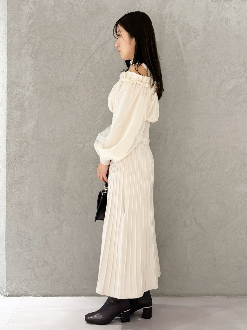 ホワイト系のワンピース、ブラウン系のブーツ、ブラウン系のハンドバッグを着用したレディースの冬コーディネートの3枚目の写真