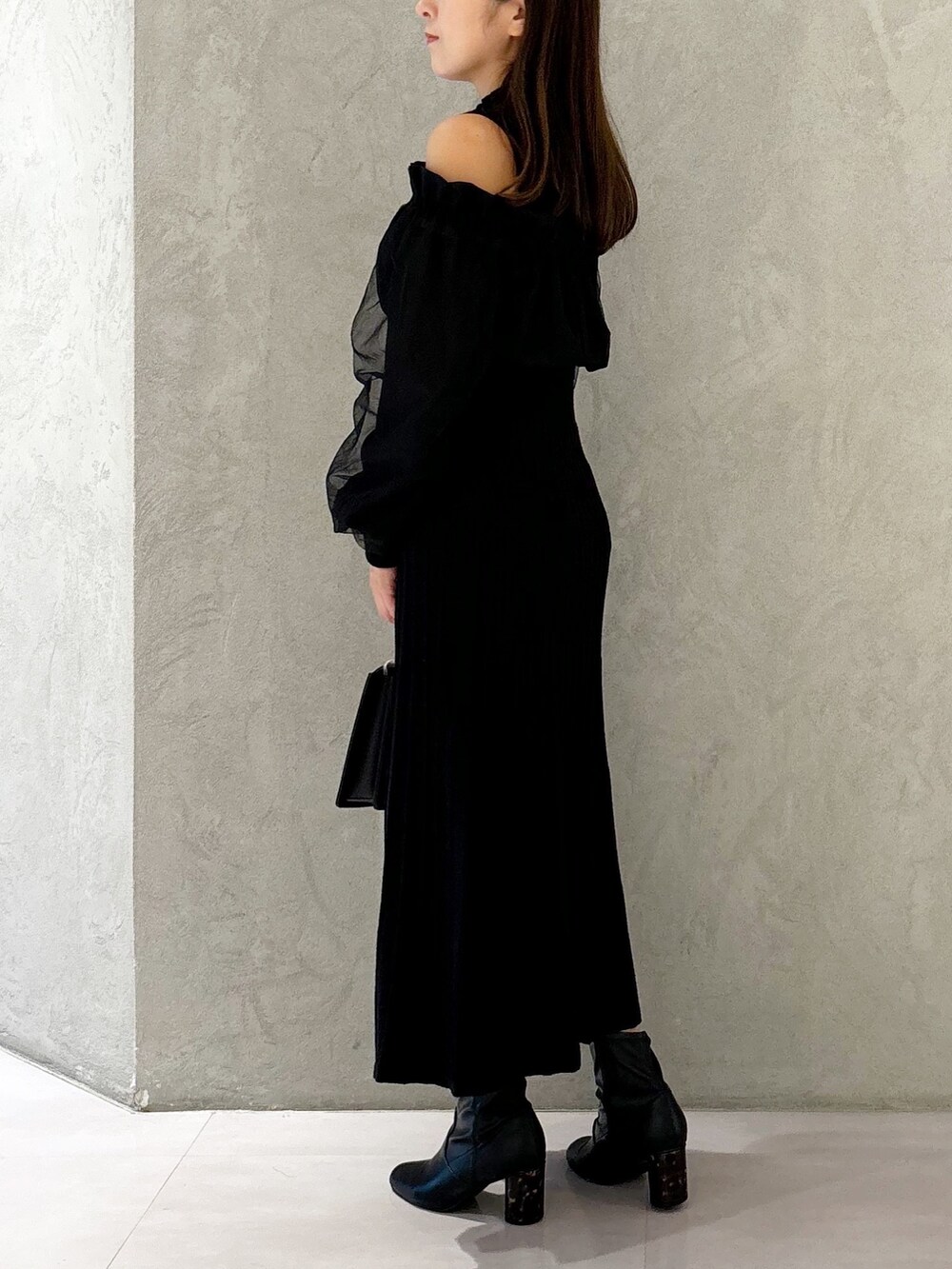 ブラック系のワンピース、ブラック系のブーツ、ブラック系のハンドバッグを着用したレディースの秋コーディネートの4枚目の写真