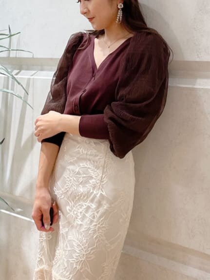 ベージュ系のショルダーバッグ、ブラウン系のカーディガン/ボレロ、ホワイト系のスカートを着用したレディースの冬コーディネートの2枚目の写真