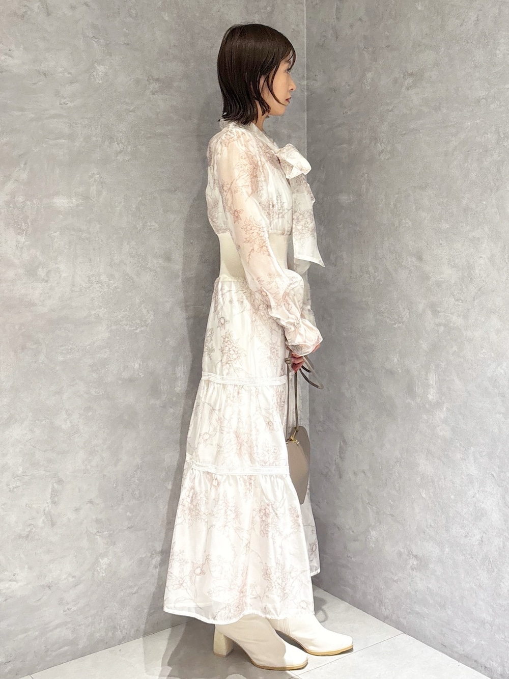 ベージュ系のショルダーバッグ、ホワイト系のブーツ、ベージュ系のワンピースを着用したレディースの冬コーディネートの2枚目の写真