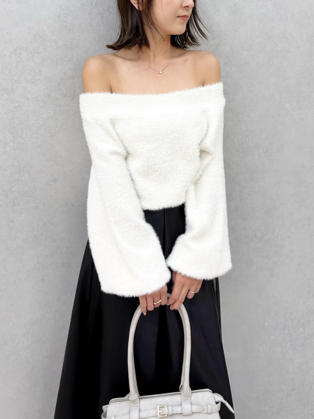 ブラック系のスカート、ホワイト系のブーツ、ホワイト系のニット/セーターを着用したレディースの秋コーディネートの3枚目の写真