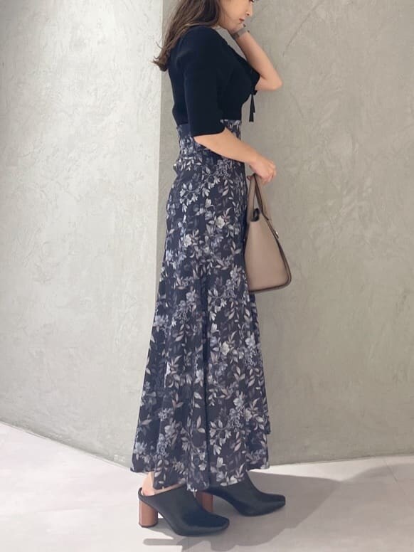 ブラック系のニット/セーター、ブラウン系のハンドバッグ、ブルー系のスカートを着用したレディースの夏コーディネートの6枚目の写真