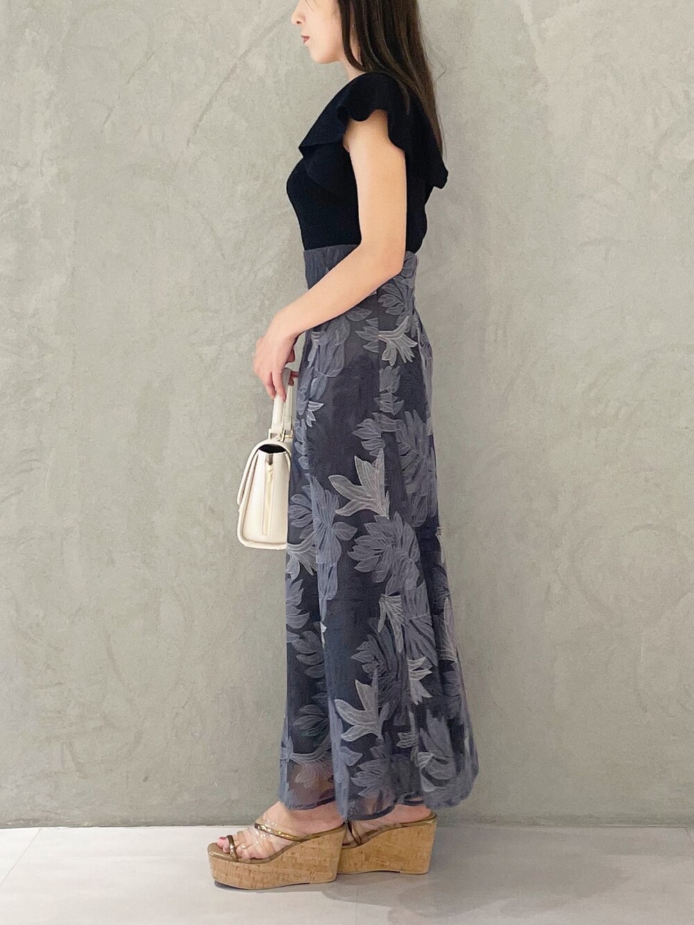 ブラック系のニット/セーター、ホワイト系のショルダーバッグ、ブラウン系のサンダルを着用したレディースの夏コーディネートの5枚目の写真