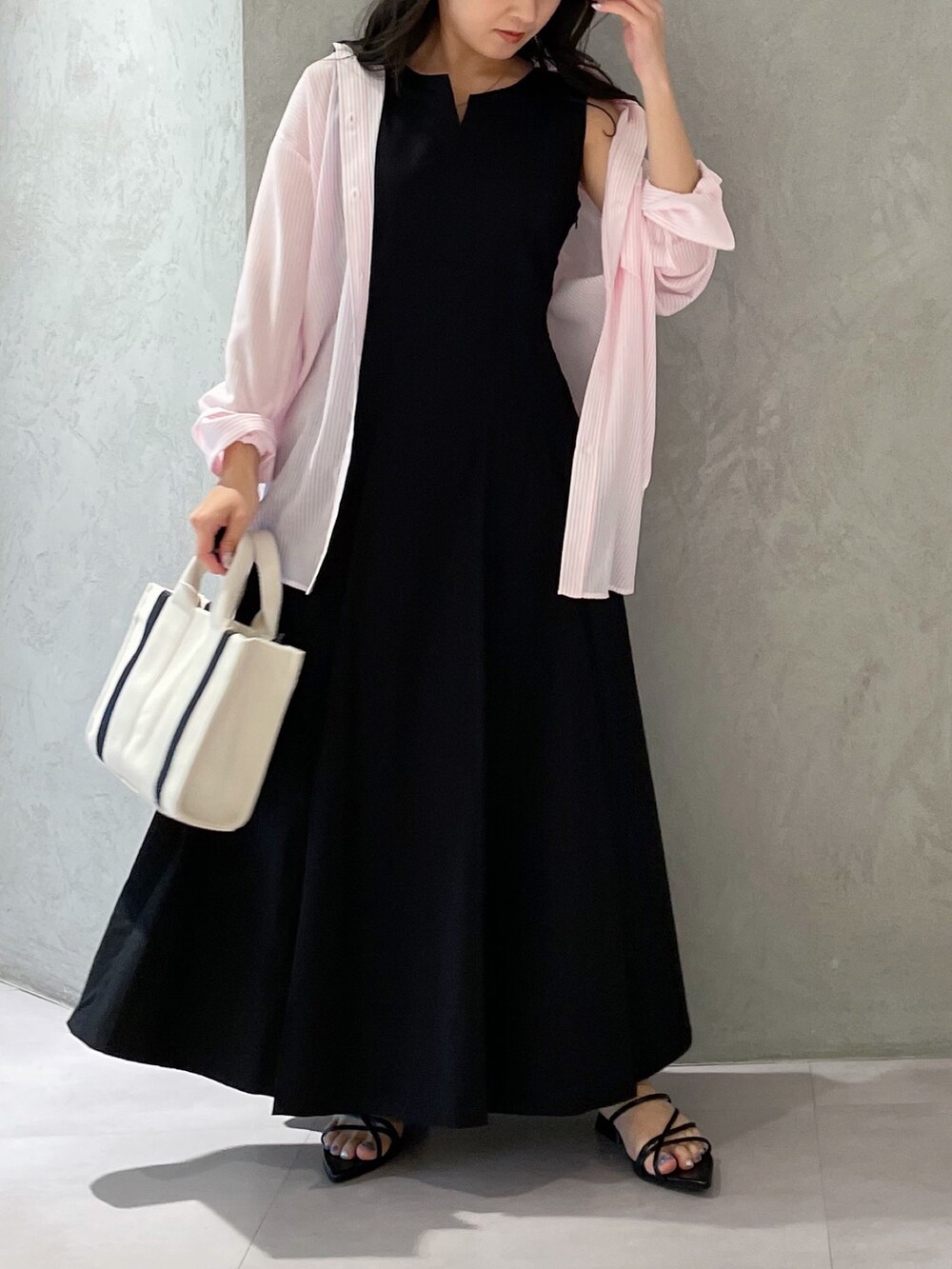 ブラック系のワンピース、ブラック系のサンダル、ホワイト系のハンドバッグを着用したレディースの春コーディネートの2枚目の写真