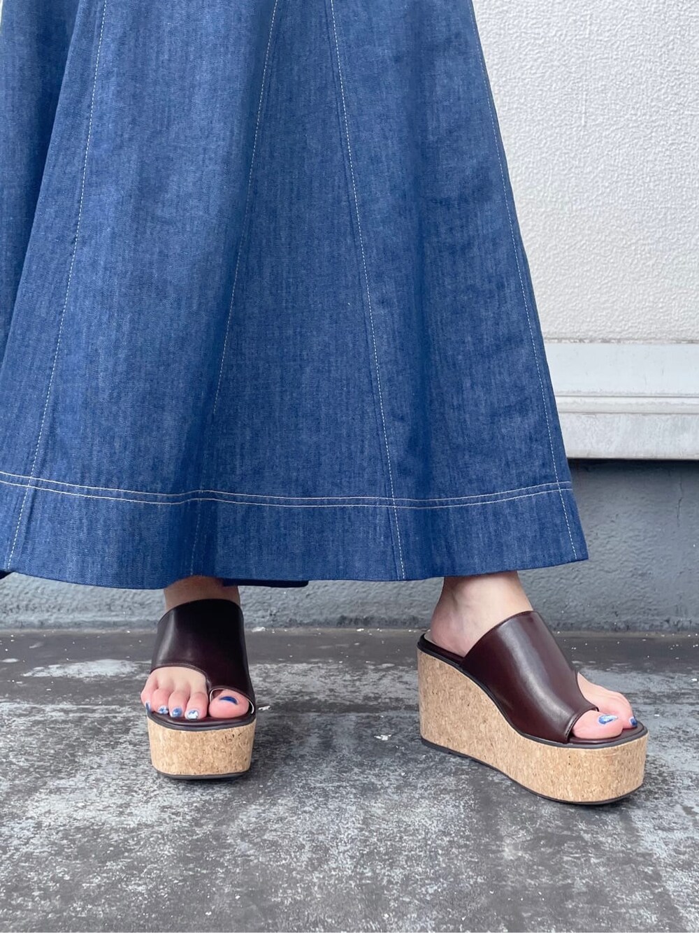 ブルー系のワンピース、ブラウン系のサンダル、ホワイト系のハンドバッグを着用したレディースの夏コーディネートの7枚目の写真