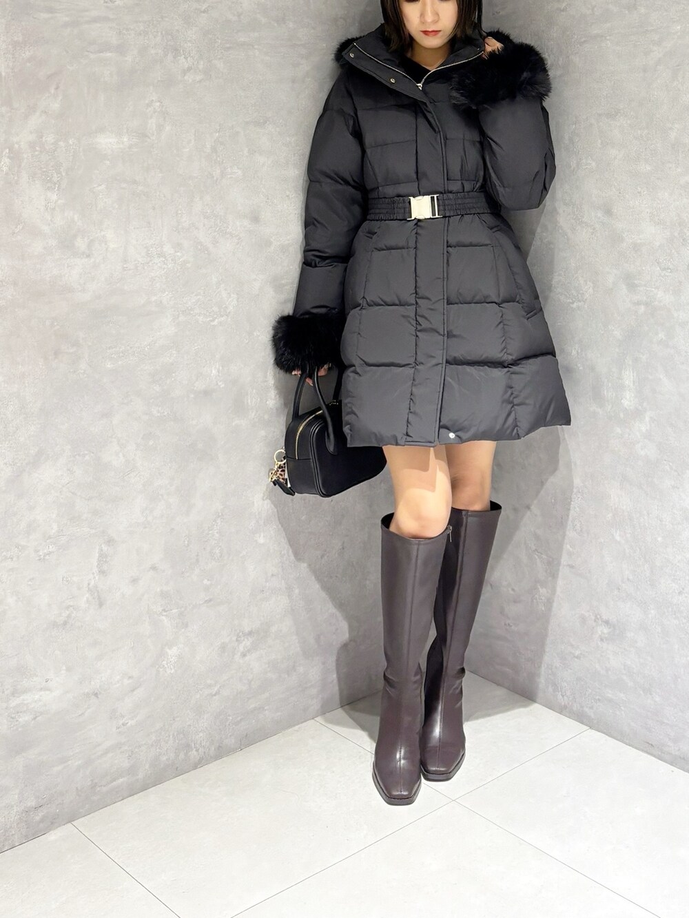 ブラウン系のブーツ、ブラック系のハンドバッグ、ブラック系のニット/セーターを着用したレディースの秋コーディネートの6枚目の写真