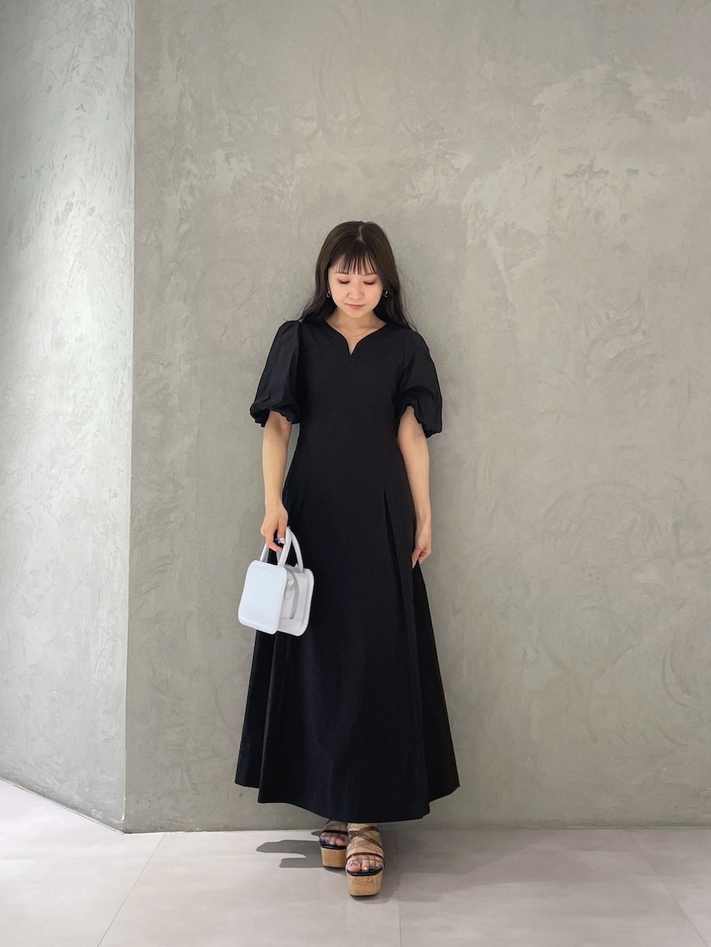 ブラック系のサンダル、ブルー系のハンドバッグ、ブラック系のワンピースを着用したレディースの春コーディネートの6枚目の写真