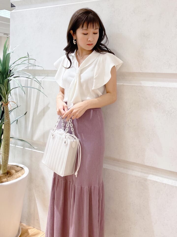 ホワイト系のハンドバッグ、ホワイト系のニット/セーター、グリーン系のサンダルを着用したレディースの春コーディネートの2枚目の写真