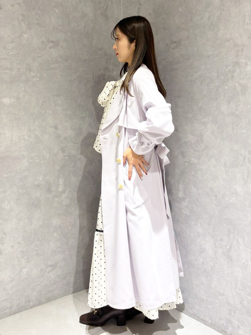 ホワイト系のワンピース、パープル系のトレンチコート、ブラウン系のハンドバッグを着用したレディースの冬コーディネートの2枚目の写真