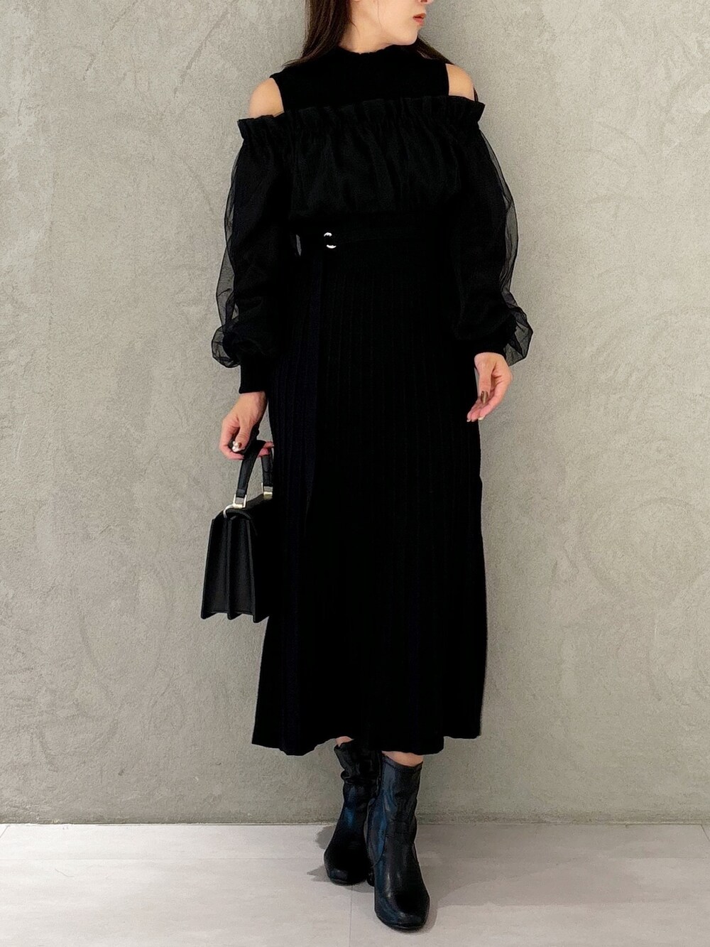 ブラック系のワンピース、ブラック系のブーツ、ブラック系のハンドバッグを着用したレディースの秋コーディネートの5枚目の写真