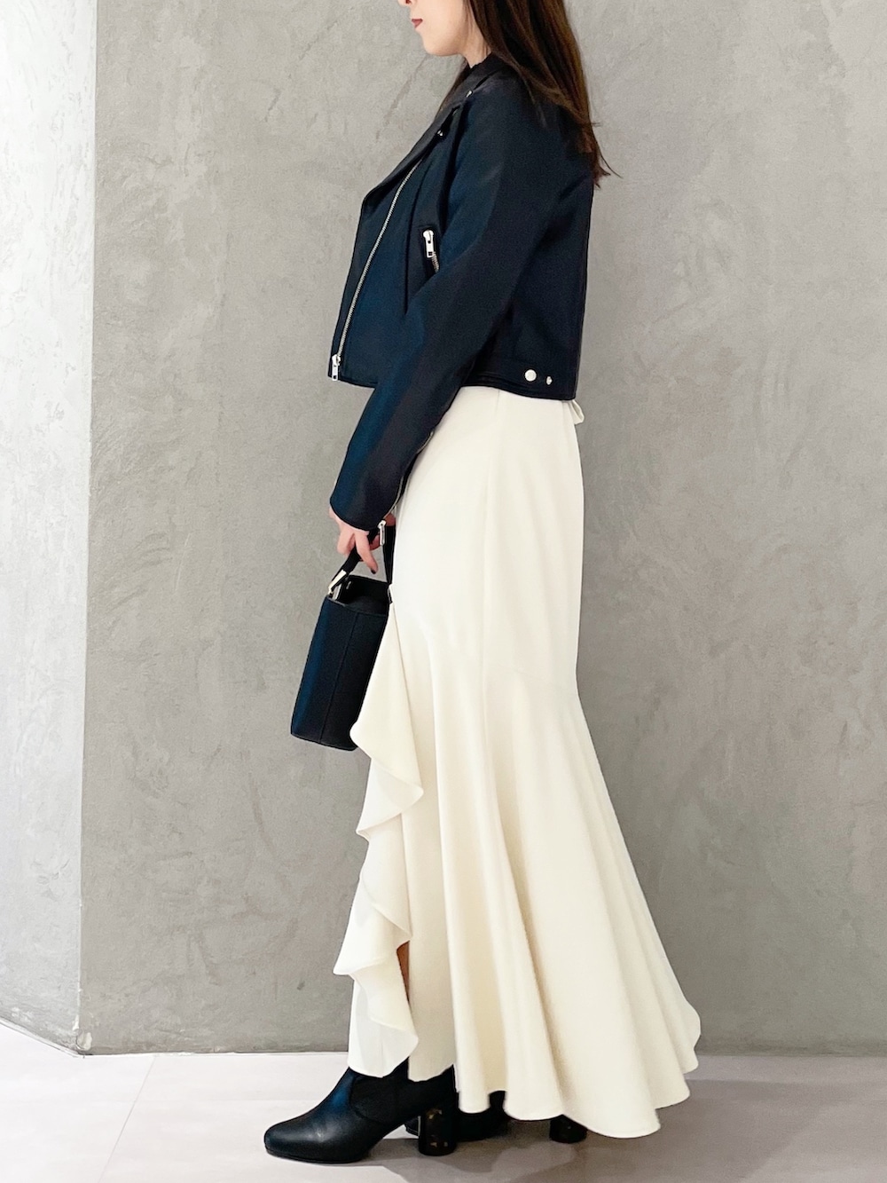 ブラック系のハンドバッグ、ブラック系のブーツ、ブラック系のライダースジャケットを着用したレディースの冬コーディネートの4枚目の写真