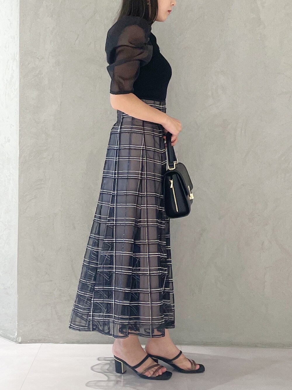 ブラック系のスカート、ブラック系のサンダル、ブラック系のショルダーバッグを着用したレディースの夏コーディネートの2枚目の写真