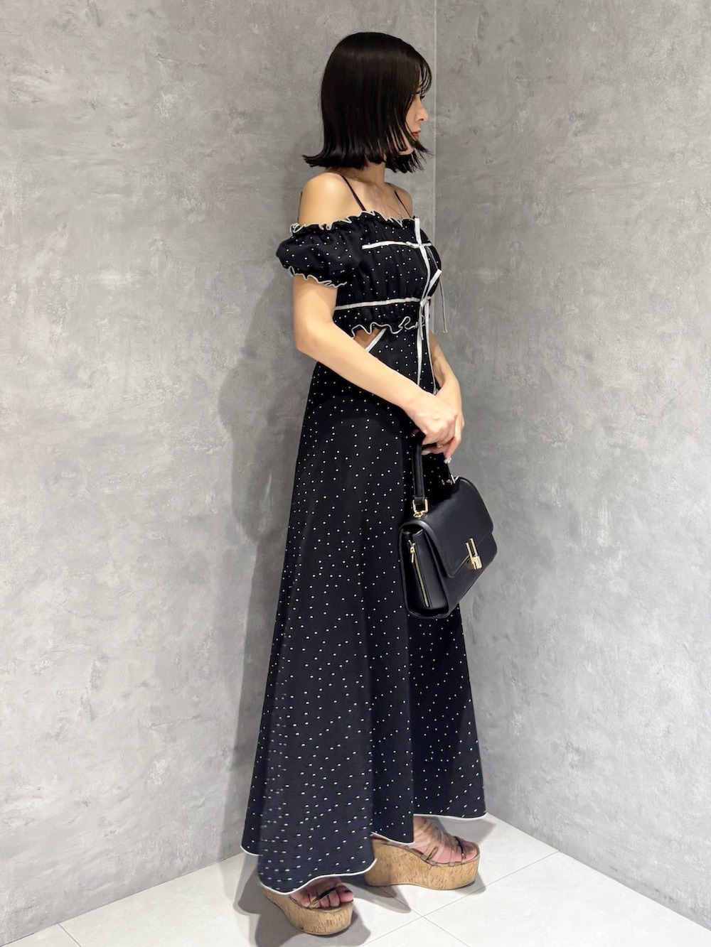 ブラック系のワンピース、ブラウン系のサンダル、ブラック系のショルダーバッグを着用したレディースの春コーディネートの2枚目の写真