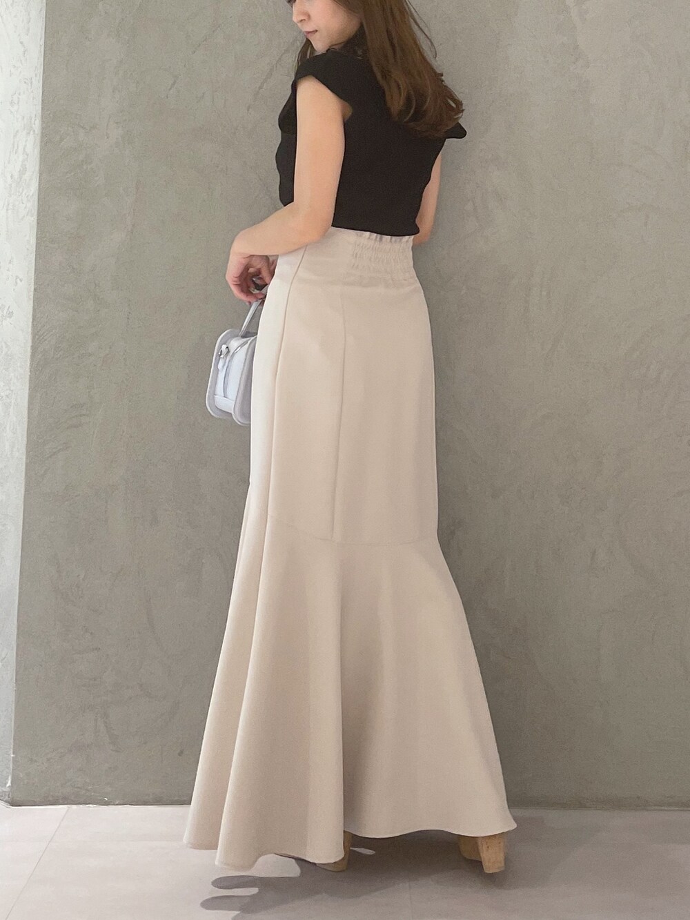 ブルー系のハンドバッグ、ブラック系のサンダル、ベージュ系のスカートを着用したレディースの春コーディネートの4枚目の写真