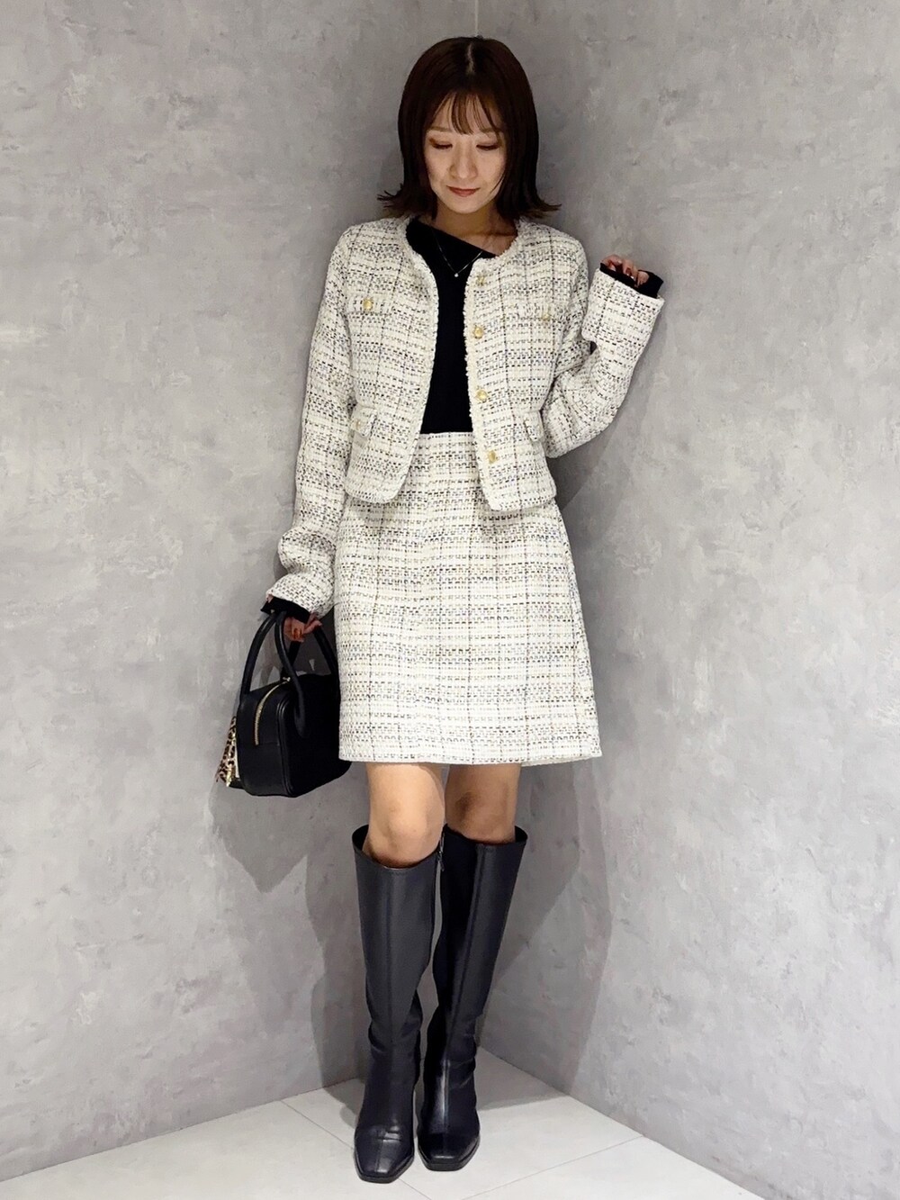 ホワイト系のスカート、ブラック系のブーツ、ブラック系のハンドバッグを着用したレディースの秋コーディネートの6枚目の写真