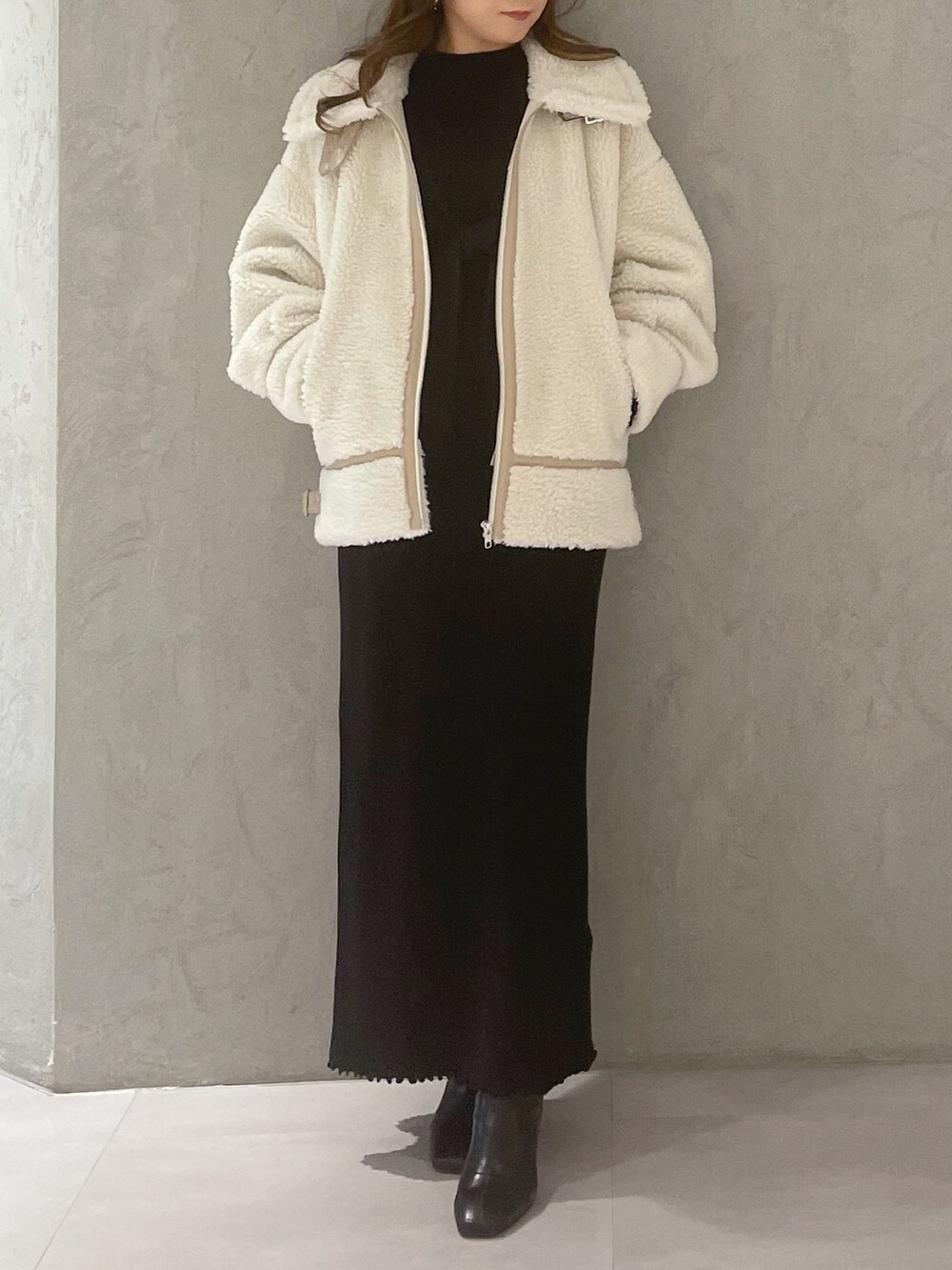 ブラック系のワンピース、ホワイト系のその他アウター、ブラック系のブーツを着用したレディースの冬コーディネートの6枚目の写真