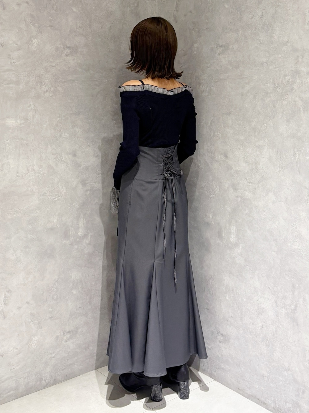 グレー系のスカート、ブラック系のハンドバッグ、ブルー系のニット/セーターを着用したレディースの冬コーディネートの4枚目の写真