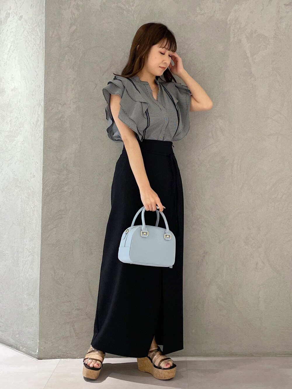 ブラック系のスカート、ブラック系のサンダル、ブルー系のボストンバッグを着用したレディースの春コーディネートの2枚目の写真