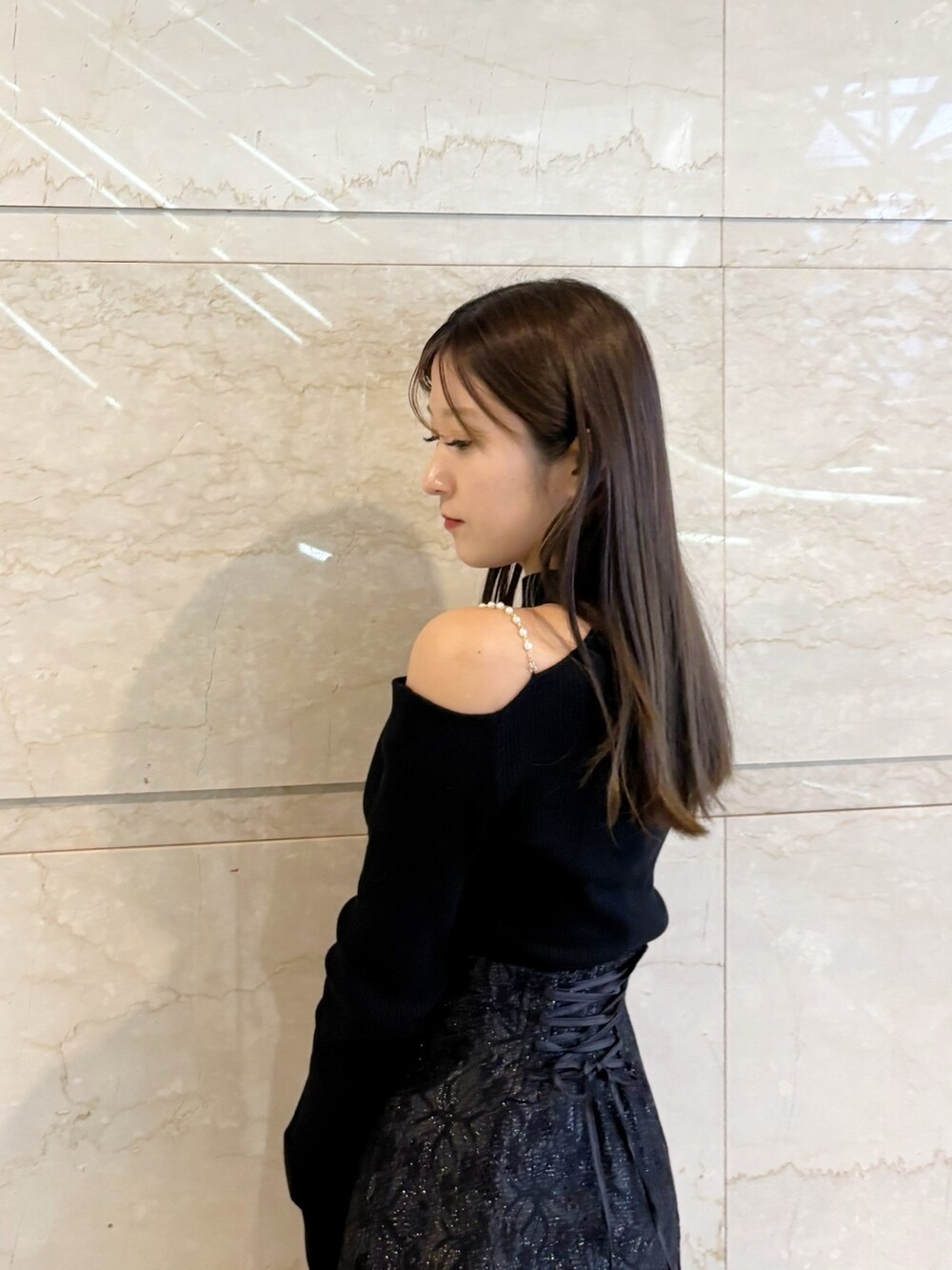 ブラック系のスカート、ブラック系のニット/セーター、ブラック系のブーツを着用したレディースの冬コーディネートの2枚目の写真