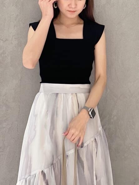 ピンク系のスカート、ブラック系のニット/セーター、ベージュ系のトートバッグを着用したレディースの夏コーディネートの2枚目の写真