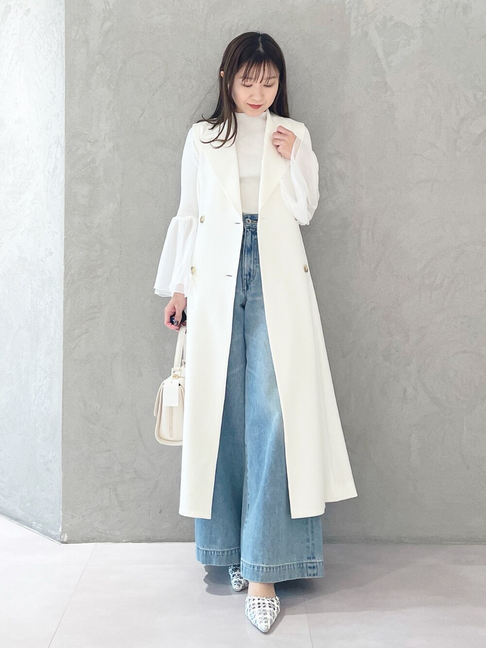 ブルー系のデニムパンツ、ホワイト系のショルダーバッグ、ホワイト系のニット/セーターを着用したレディースの冬コーディネートの5枚目の写真