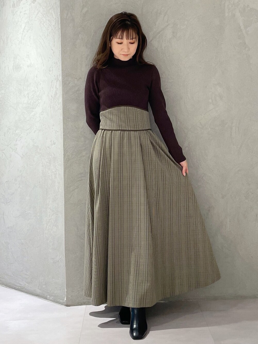 ブラウン系のワンピース、ブラック系のブーツを着用したレディースの冬コーディネートの7枚目の写真