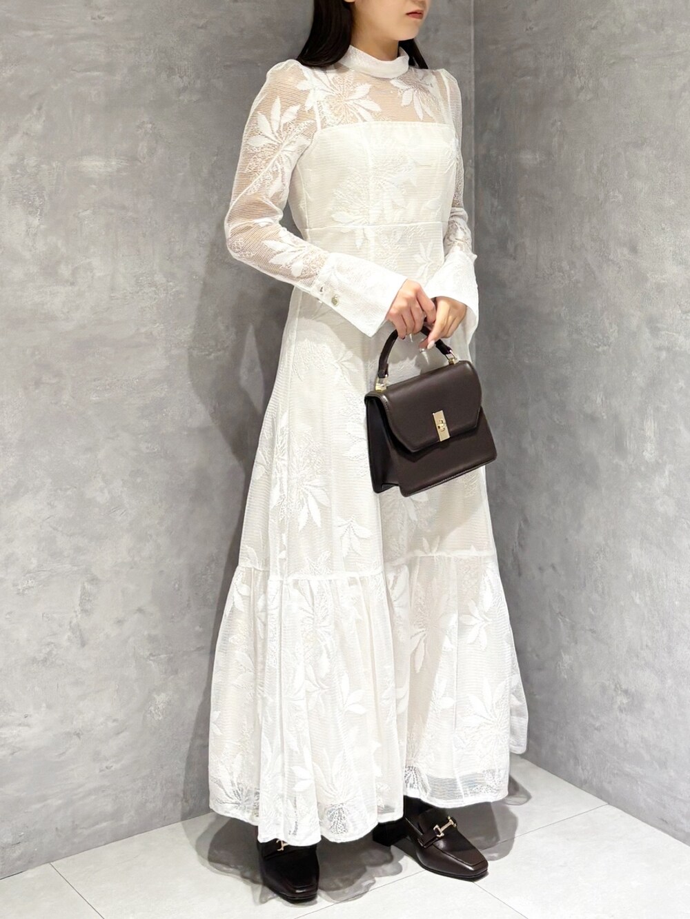 ホワイト系のワンピース、ブラウン系のハンドバッグ、ブラウン系のブーツを着用したレディースの冬コーディネートの5枚目の写真