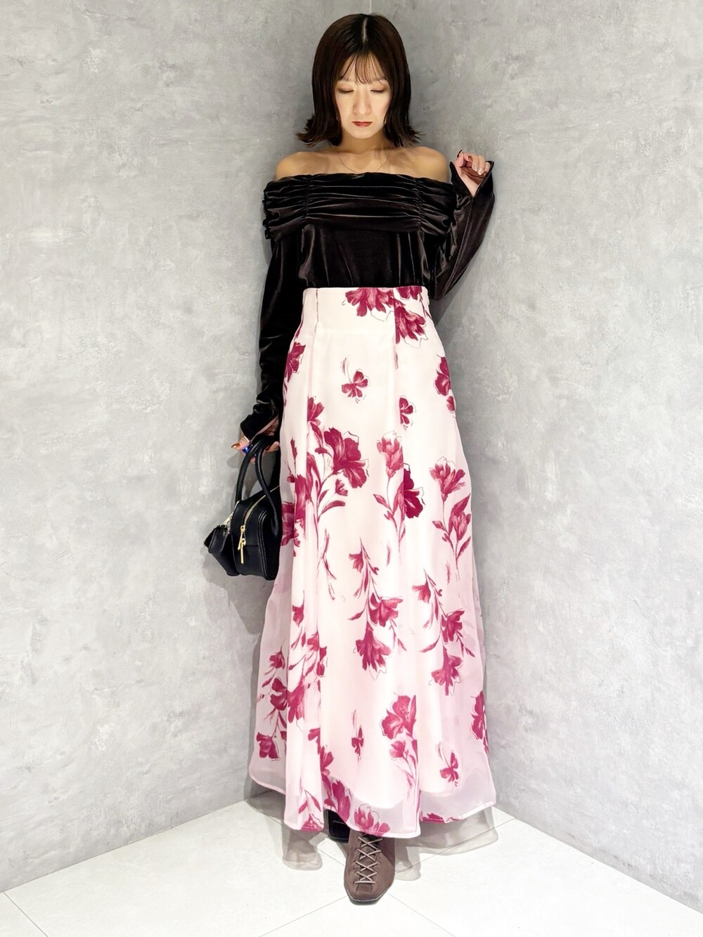 ブラック系のハンドバッグ、ブラウン系のTシャツ/カットソー、ピンク系のスカートを着用したレディースの秋コーディネートの5枚目の写真