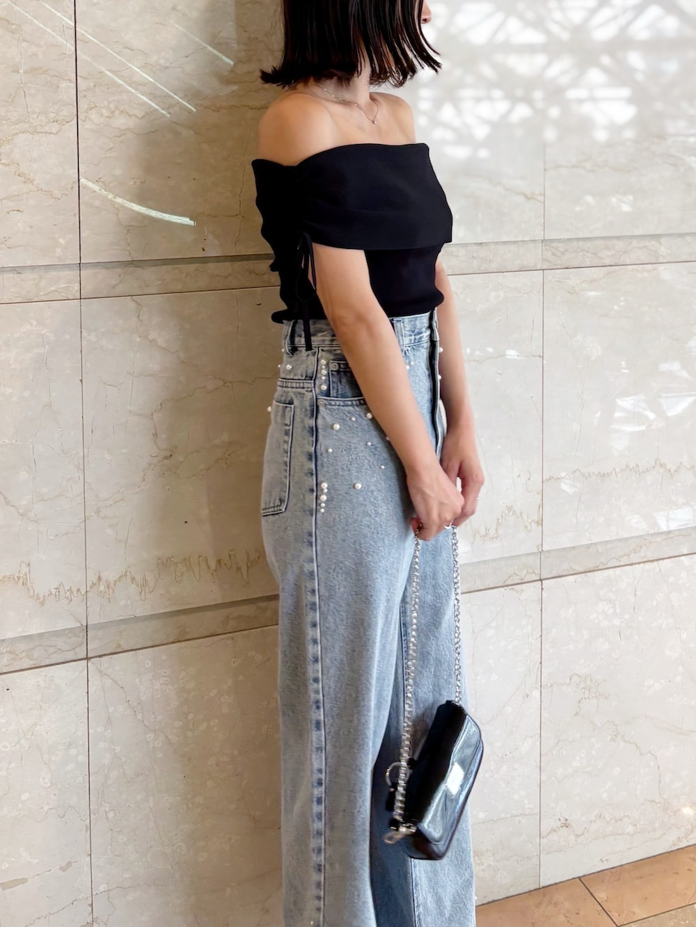 ブラック系のボディバッグ/ウエストポーチ、ブラック系のニット/セーター、ブルー系のデニムパンツを着用したレディースの夏コーディネートの6枚目の写真