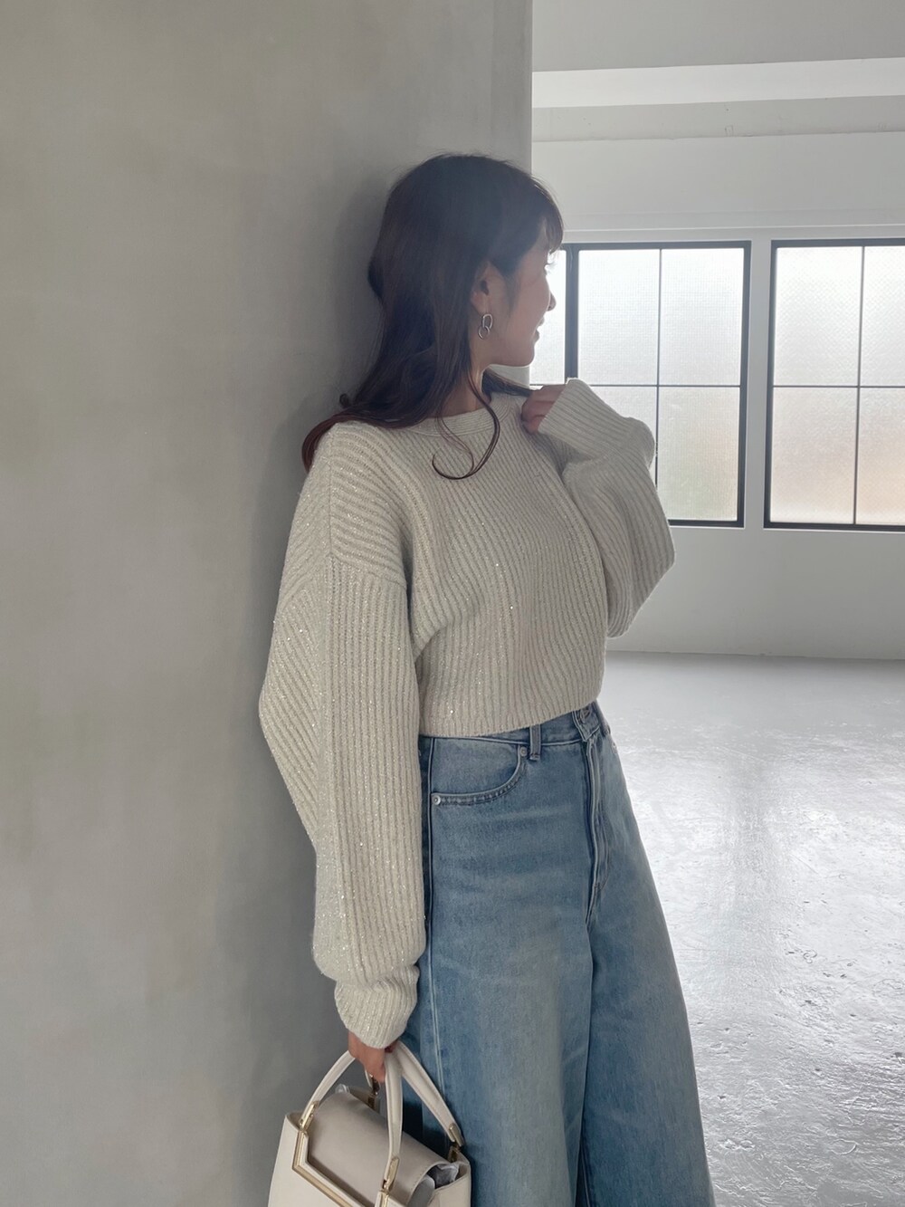 ホワイト系のブーツ、ホワイト系のハンドバッグ、ブルー系のデニムパンツを着用したレディースの秋コーディネートの6枚目の写真