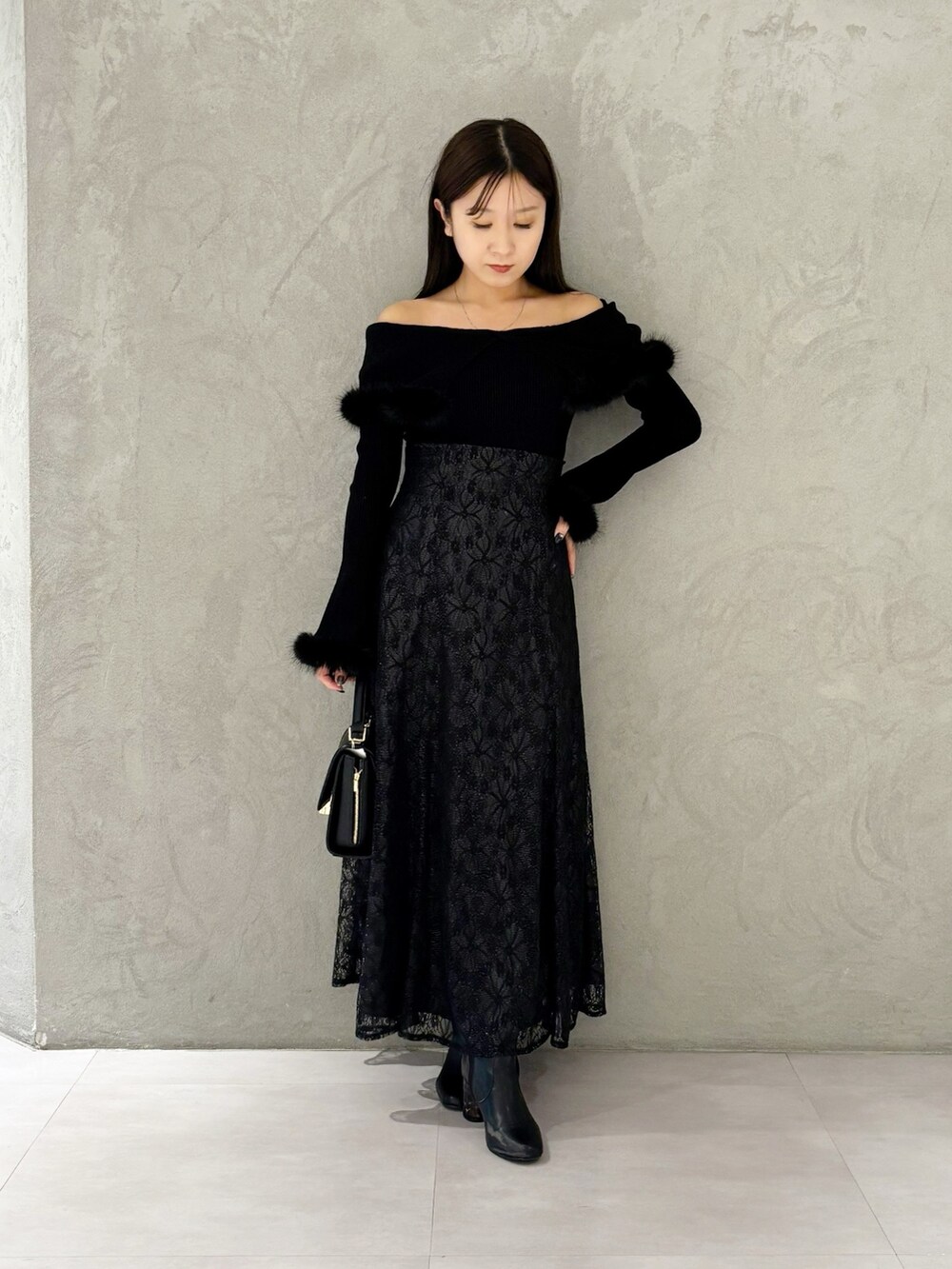 ブラック系のスカート、ブラック系のブーツ、ブラック系のショルダーバッグを着用したレディースの冬コーディネートの8枚目の写真