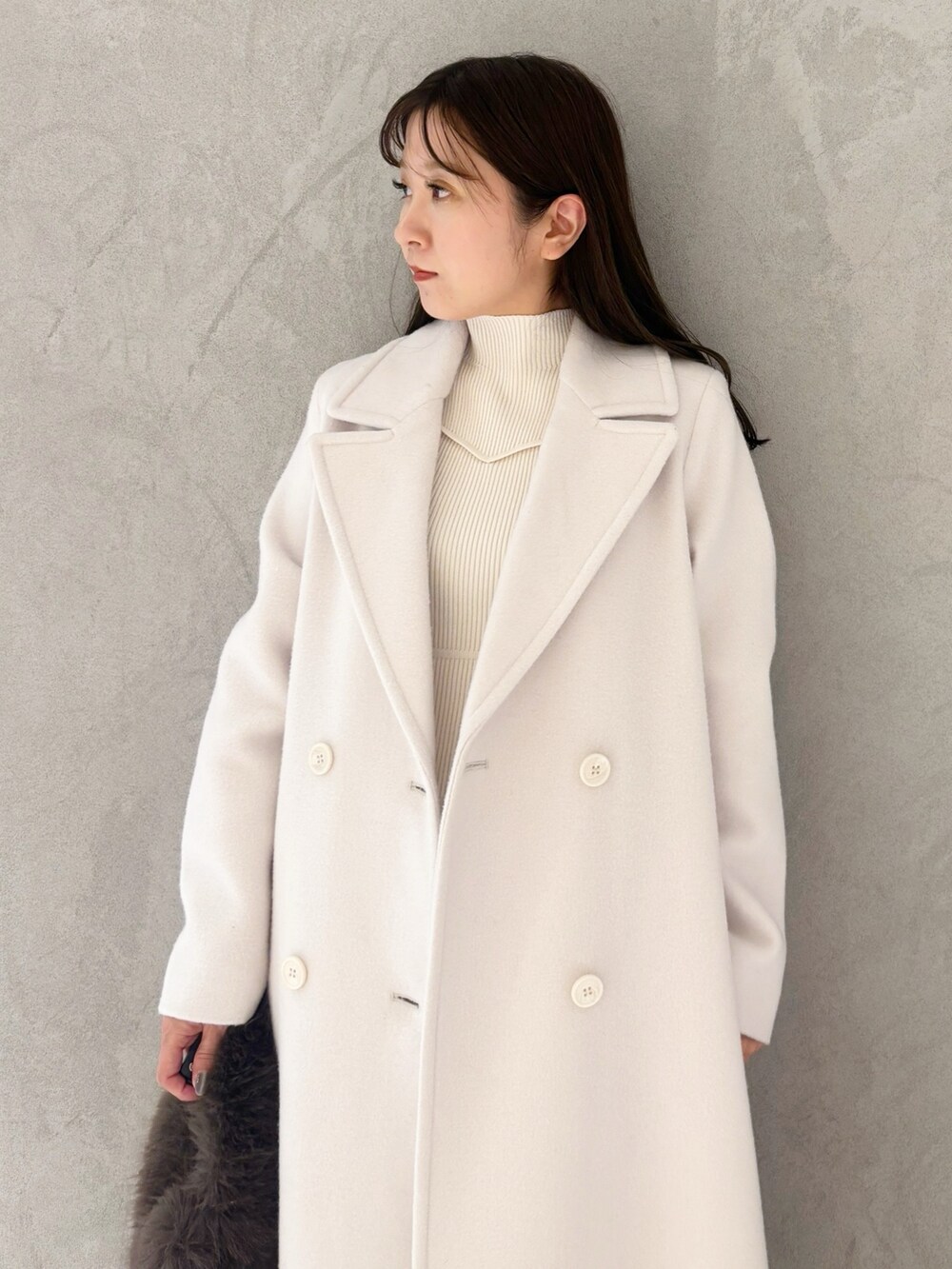 ホワイト系のチェスターコート、ブラック系のブーツ、ブラウン系のハンドバッグを着用したレディースの冬コーディネートの4枚目の写真