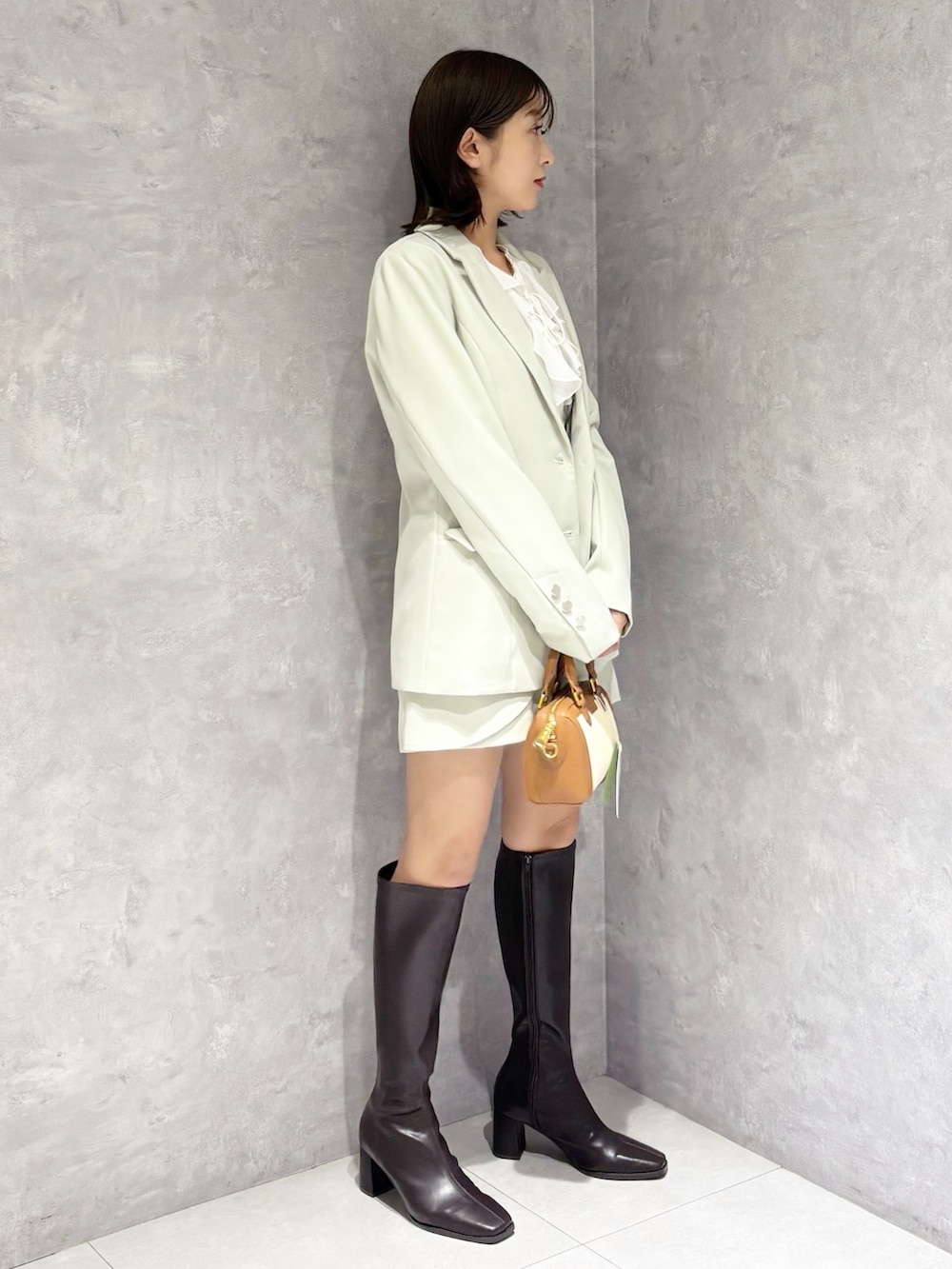 グリーン系のスカート、ブラウン系のブーツ、グリーン系のテーラードジャケットを着用したレディースの春コーディネートの3枚目の写真