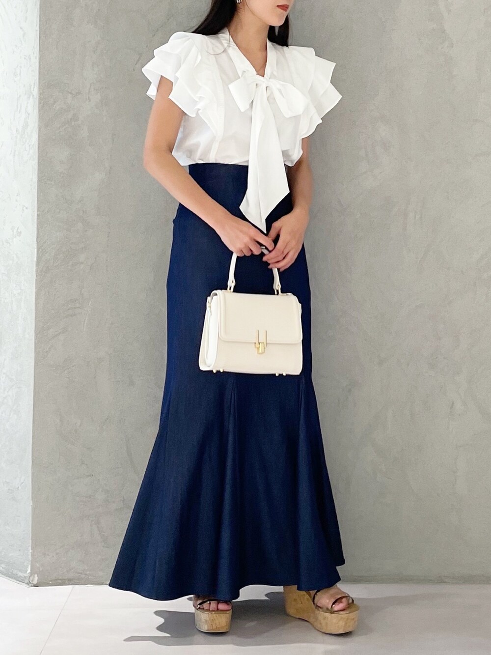 ブルー系のスカート、ブラウン系のサンダル、ホワイト系のショルダーバッグを着用したレディースの夏コーディネートの4枚目の写真