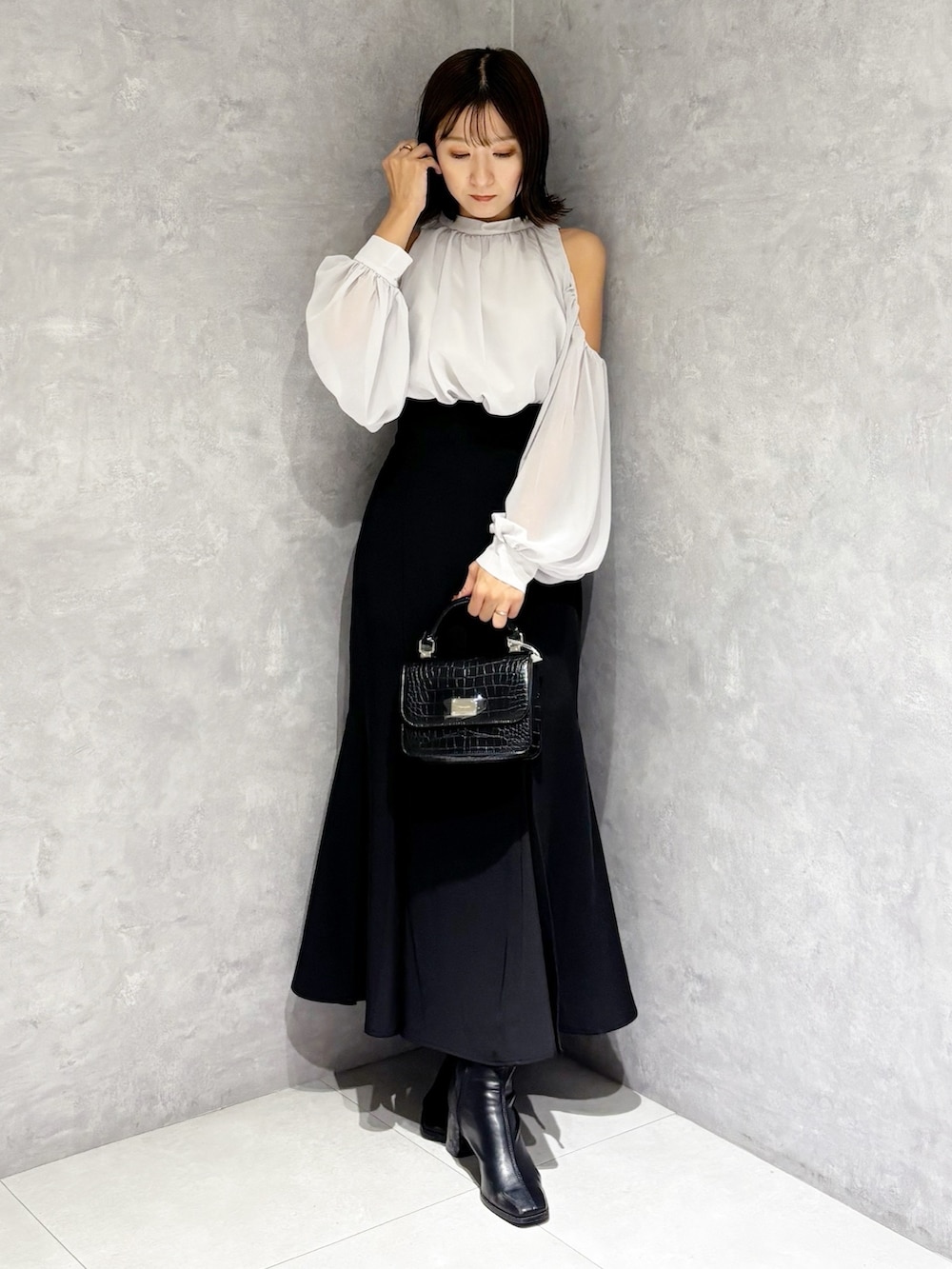 ブラック系のハンドバッグ、ブラック系のブーツ、ブラック系のスカートを着用したレディースの秋コーディネートの8枚目の写真