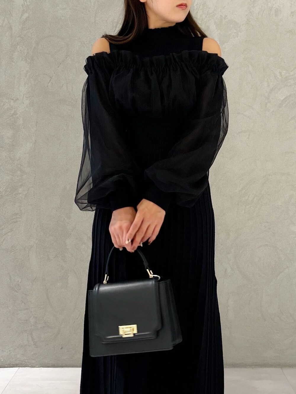 ブラック系のワンピース、ブラック系のブーツ、ブラック系のハンドバッグを着用したレディースの秋コーディネートの2枚目の写真